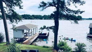 A lakeside cabin with a dock extending into the water, surrounded by trees. - A Modern-Rustic Lake Retreat Get-Away! (Milledgeville)