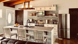 A modern kitchen with a central island, white cabinetry, and stainless steel appliances. - A Modern-Rustic Lake Retreat Get-Away! (Milledgeville)