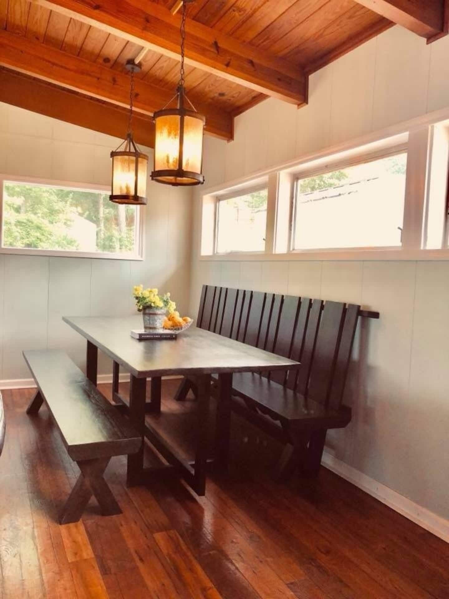 A dining area with a wooden table, benches, and pendant lighting.