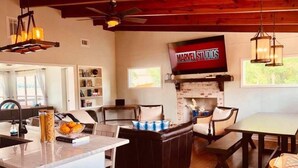 A cozy living room with a fireplace, a television mounted on the wall, and a dining area with a table and chairs. - A Modern-Rustic Lake Retreat Get-Away! (Milledgeville)