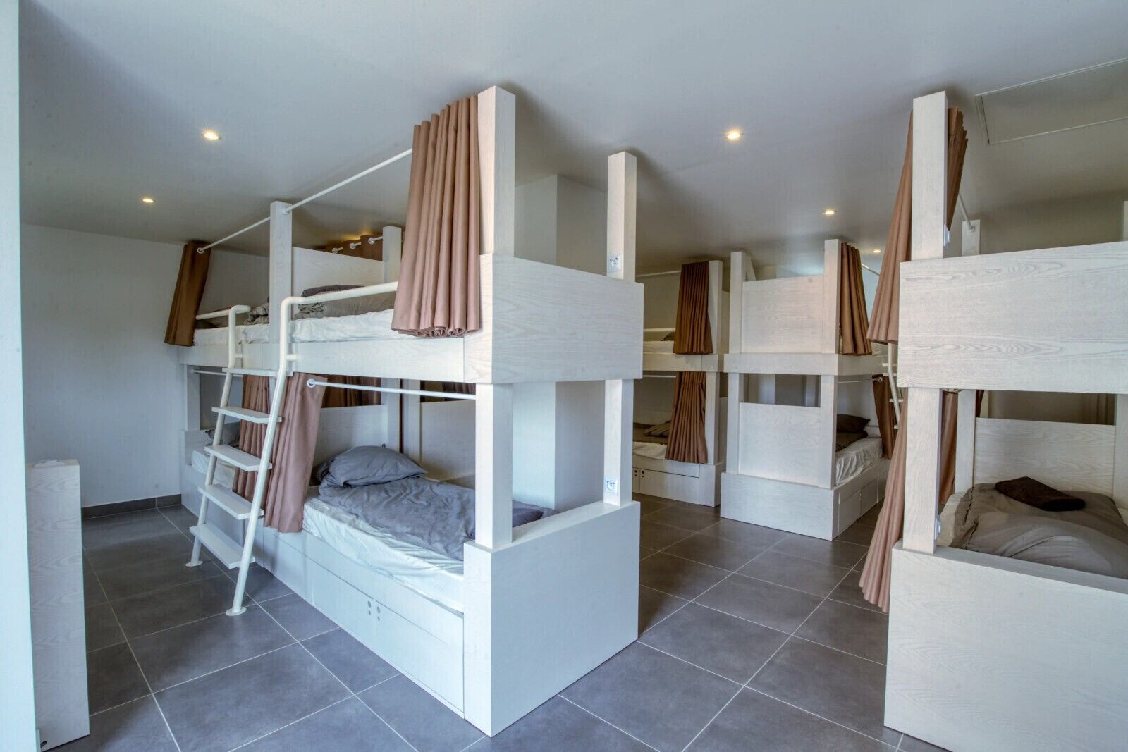 Habitació amb llits superposats, escala i cortines.