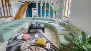 A living room with a large L-shaped green sofa, a black coffee table, and a staircase leading to another room. - So Villa Buisson (41) - Heated swimming pool - Volleyball - 2h from Paris- 30p. (Couëtron-au-Perche)