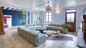 A spacious living room with a sectional sofa, a coffee table, and a large window providing natural light. - So Villa Buisson (41) - Heated swimming pool - Volleyball - 2h from Paris- 30p. (Couëtron-au-Perche)