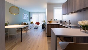 Eine moderne Küche mit Essbereich, Holzschränken und einem großen Fenster.