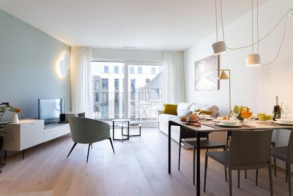 Una sala de estar moderna con comedor, ventanas amplias y un balcón.