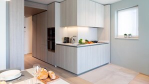 Eine moderne Küche mit einer zentralen Kochinsel, integrierten Geräten und einem Fenster mit Pflanzen.