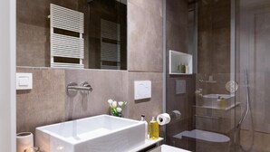 Un baño moderno con una bañera grande, un inodoro y una zona de ducha con mampara de cristal.