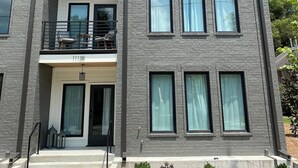 Ein mehrstöckiges Gebäude mit Backsteinfassade, großen Fenstern und einem Balkon mit Außenmöbeln.