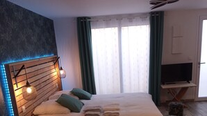 Un dormitorio moderno con cabecera de madera, televisión de pantalla plana y suelo de madera.