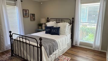 A bedroom with a bed, a ceiling fan, a nightstand, a lamp, and a window with blinds.