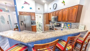 A kitchen with wooden cabinets, a granite countertop, and a built-in island with bar stools. - Bring your Boat & Enjoy Crystal River! Fish & See Manatee at Our Dock, Kayaks (Crystal River)