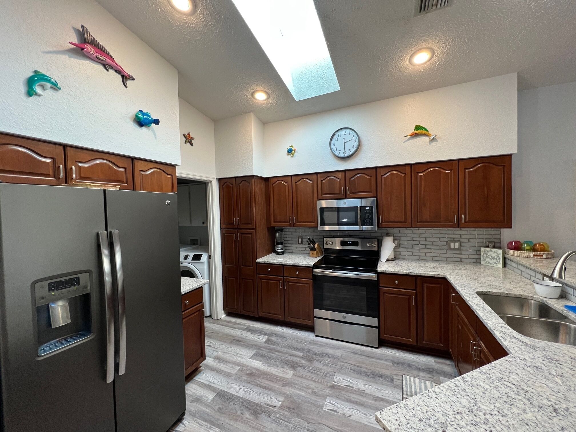 A modern kitchen with wooden cabinets, stainless steel appliances, and a built-in microwave.