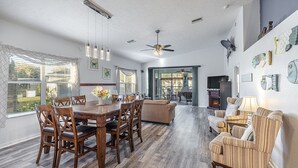A spacious dining area with a wooden table and chairs, a ceiling fan, and a view of the outdoors through large windows. - Bring your Boat & Enjoy Crystal River! Fish & See Manatee at Our Dock, Kayaks (Crystal River)