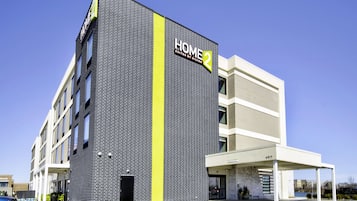 Un hotel moderno con un llamativo letrero de "HOME 2", fachada de ladrillo y una zona de acceso cubierta.