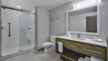 A modern bathroom with a glass-enclosed shower, a toilet, and a vanity with a mirror and sink.
