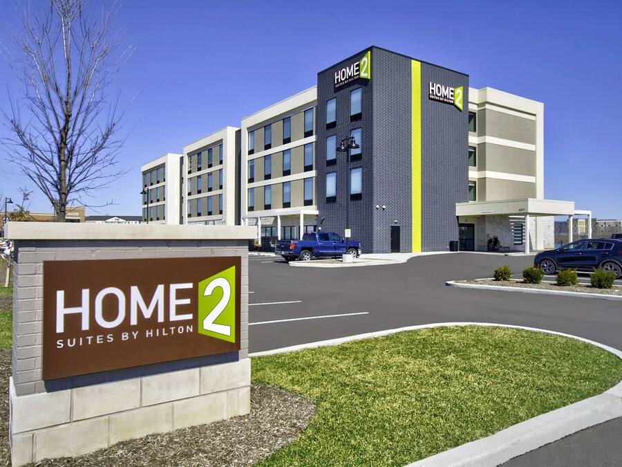 A modern hotel building with a sign reading "HOME 2 Suites by Hilton."