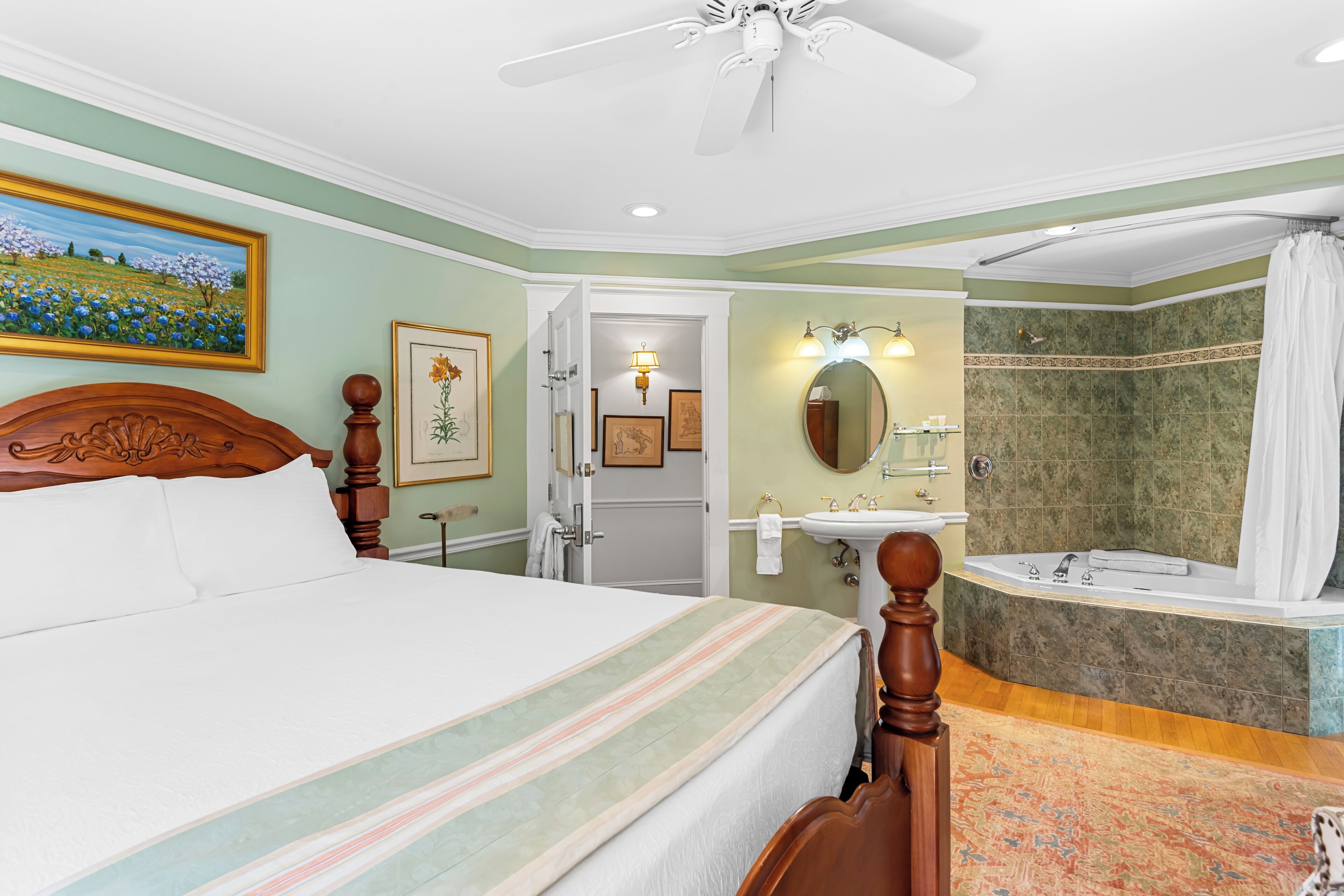 A bedroom with a bed, a bathroom with a sink and bathtub, and a ceiling fan.