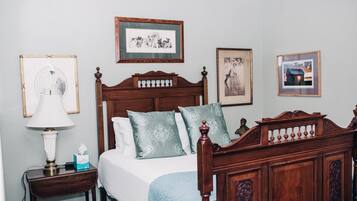 A neatly made bed with a wooden headboard, a bedside table with a lamp, and framed pictures on the wall.