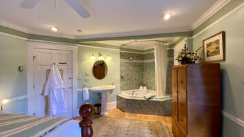 A bedroom with a bed, a vanity, a bathtub, and a ceiling fan.