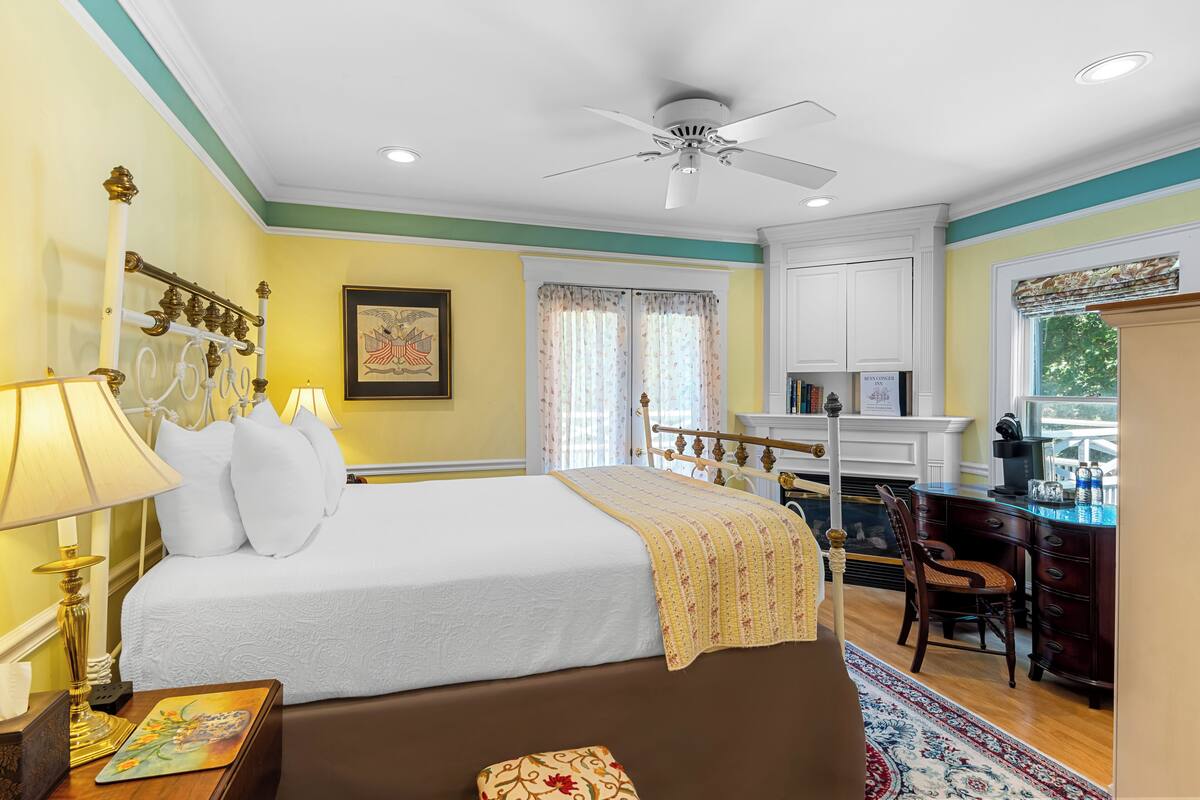 A neatly arranged bedroom with a bed, bedside table, lamp, and a desk with a chair.