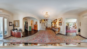 Ein prachtvoller Eingangsbereich mit großem, aufwendig gestaltetem Teppich, einer Treppe und einem Chandelier.