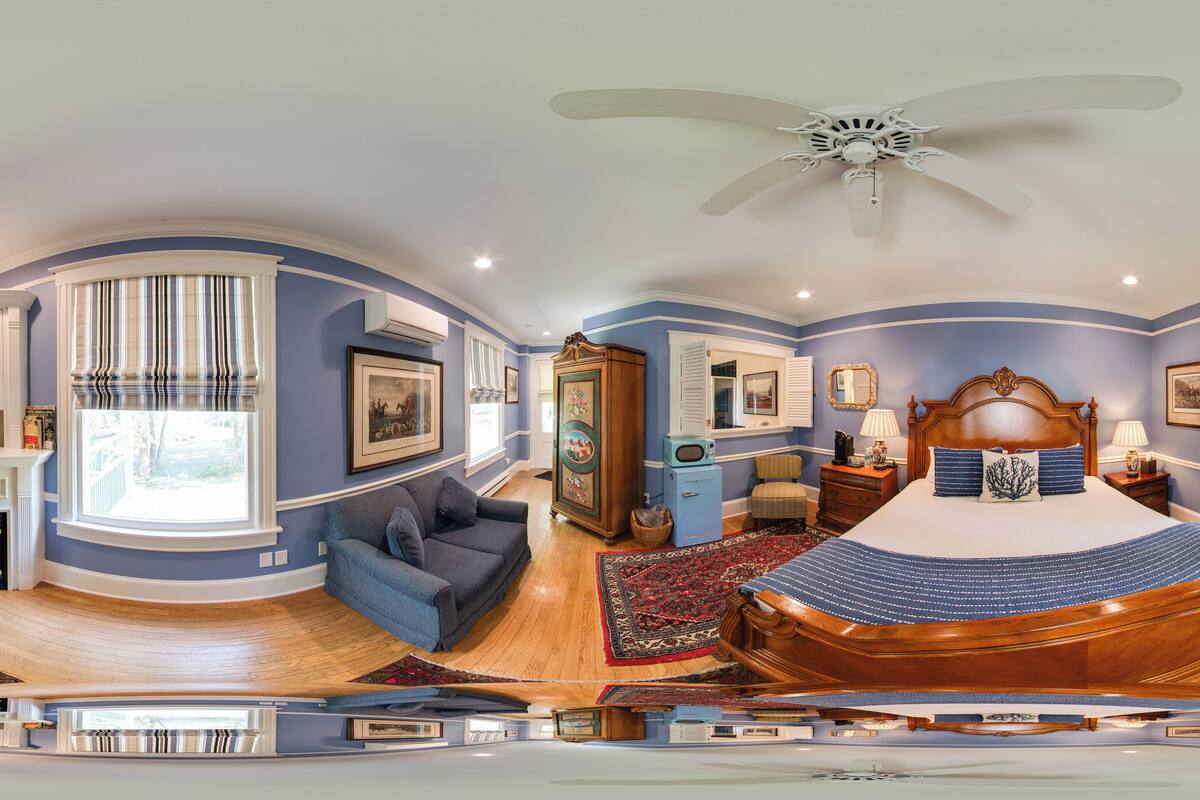 A bedroom with a large bed, a ceiling fan, and a view of the outside.