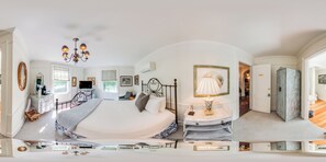 A bedroom with a large bed, bedside tables, a vanity with a mirror, and a chandelier.