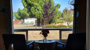 A dining area with a table and chairs facing a window with a view of trees and a parked vehicle outside. - Olympic  Adventure Home, Your Gateway To Adventure And Olympic National Park (Port Angeles)