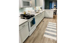 Une cuisine moderne avec des meubles blancs, un four à micro-ondes, une cuisinière et un évier.