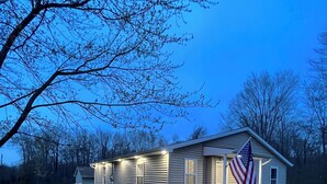 Une maison de plain-pied avec un porche à l’avant, un drapeau américain et une pelouse bien entretenue.