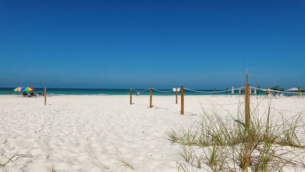 A beach with white sand, a clear blue sky, and a few umbrellas. - Anchorage 211 in Siesta Key (Siesta Key)
