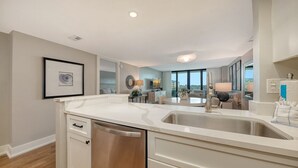 A modern kitchen with a central island, stainless steel appliances, and a view to the living area. - Anchorage 507 (Siesta Key)