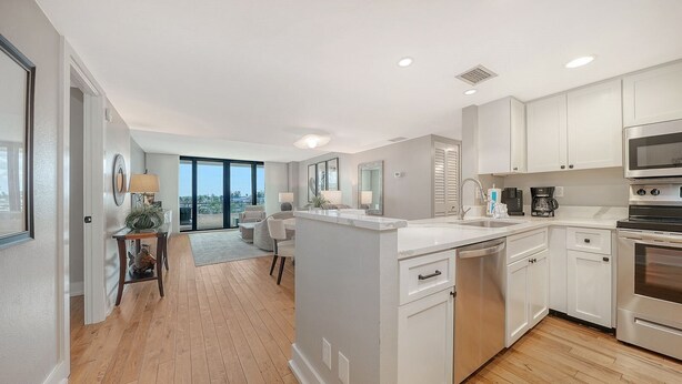 A modern kitchen with white cabinetry, stainless steel appliances, and a view to the outside. - Anchorage 507 (Siesta Key)