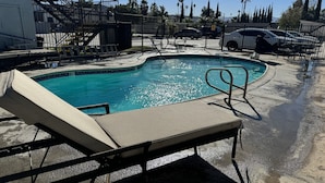 A swimming pool with a sun lounger and a metal ladder. - Sands Motel (Riverside)