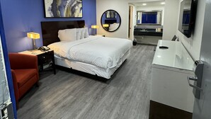 A hotel room with a bed, bedside table, lamp, and a bathroom with a sink and mirror. - Sands Motel (Riverside)