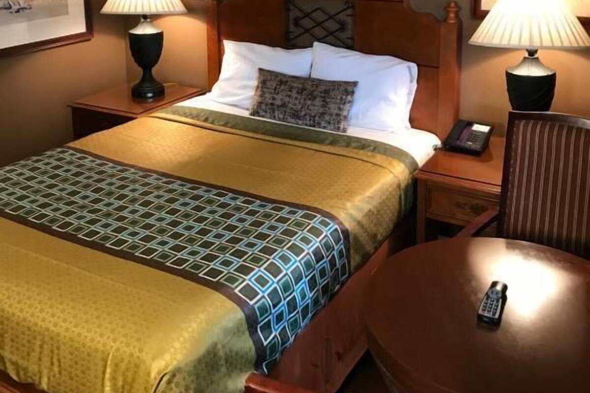 Ein Hotelzimmer mit einem Bett, zwei Nachttischen mit Lampen, einem Sessel und einem kleinen Tisch.