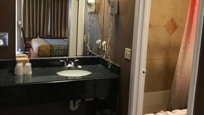 A bathroom with a sink, mirror, and a shower area. - Sands Motel (Riverside)