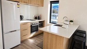 Une cuisine moderne équipée d’un four encastré, d’un réfrigérateur et d’une fenêtre donnant sur les montagnes.