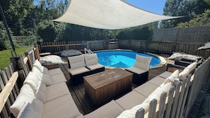 A backyard with a swimming pool, outdoor furniture, and a canopy.