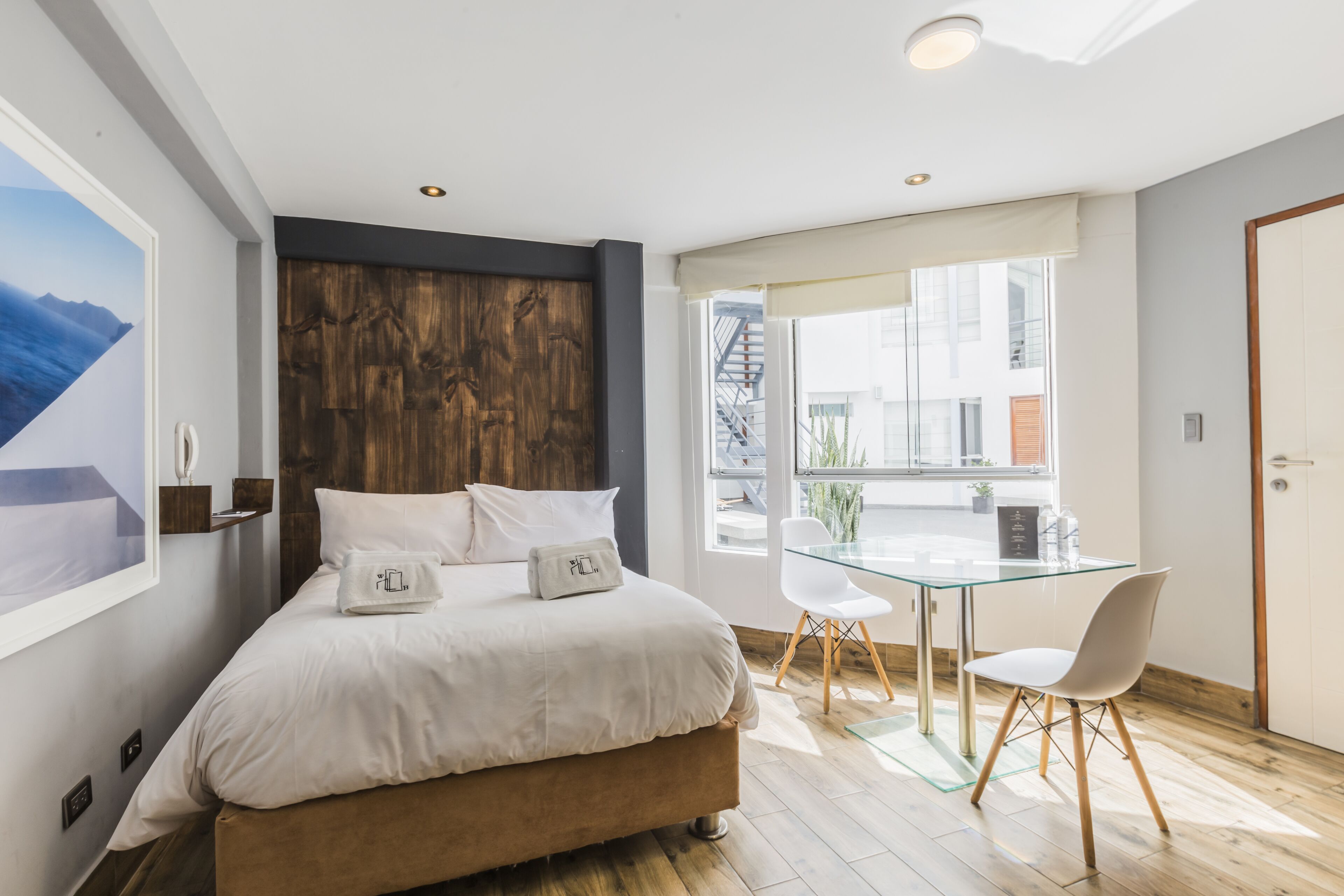Un dormitorio con una cama, una mesita de vidrio y una silla.