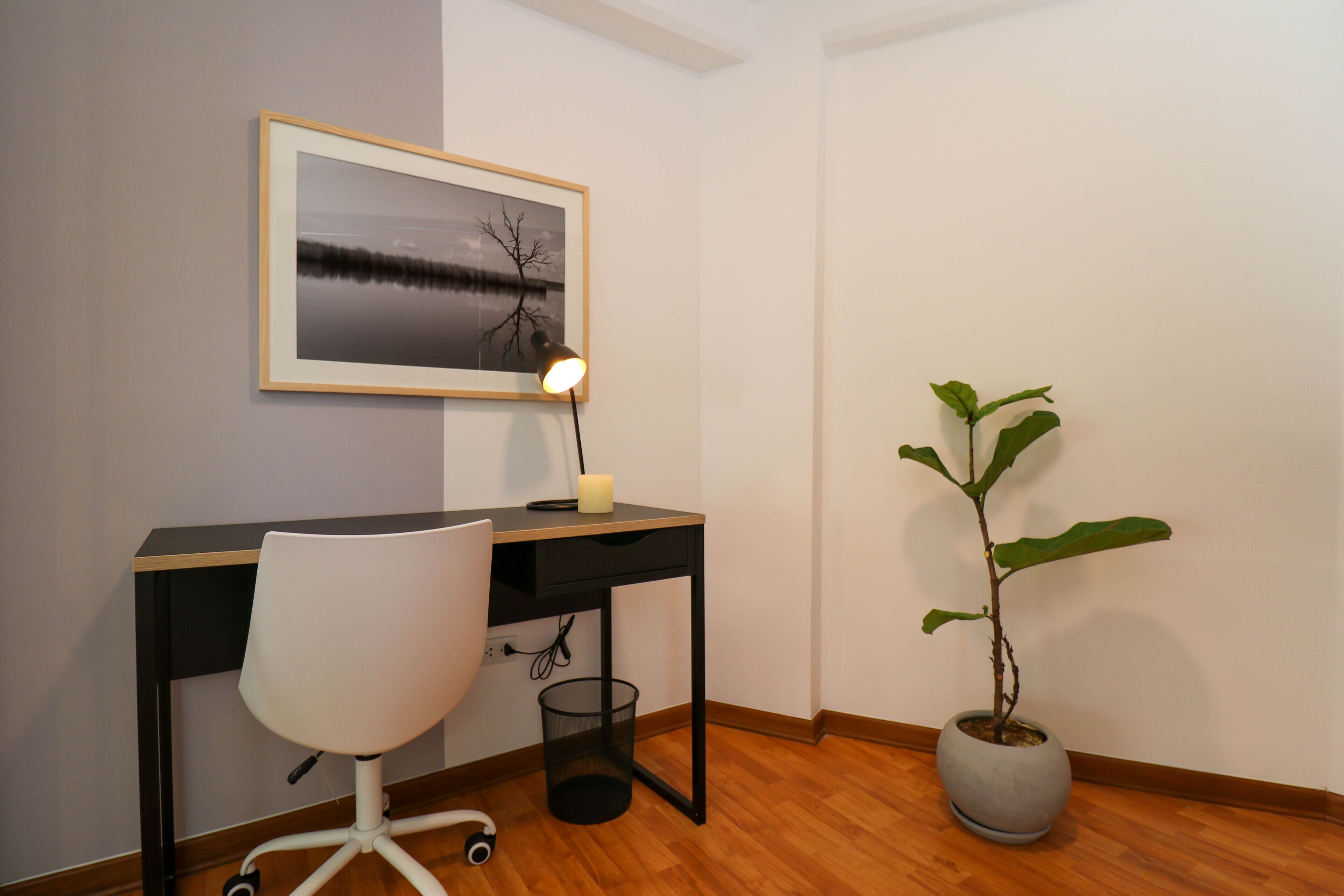 A workspace with a desk, chair, lamp, and a potted plant.
