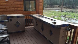 Une terrasse en bois avec un barbecue intégré et une petite table.