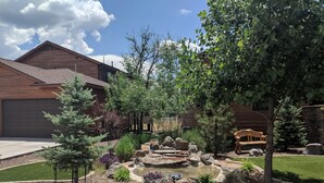 Un quartier résidentiel comprenant une maison en bois, un petit étang avec des rochers et diverses plantes.