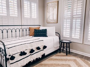 Quarto com uma cama, uma cadeira e uma janela com persianas.