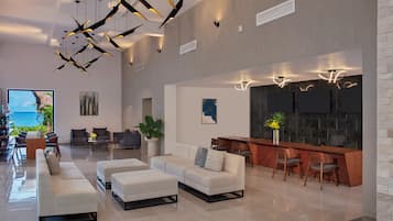 Una sala de estar moderna con un conjunto de sofás, una mesa de centro y un comedor con sillas. Hay un televisor de pantalla plana grande montado en la pared y una planta en la esquina.