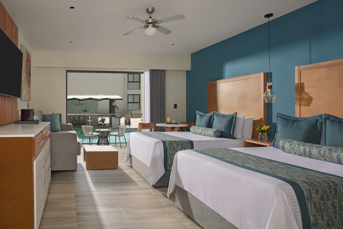 A hotel room with two beds, a dining area, and a view of the pool.