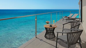 A balcony with clear blue ocean views, two lounge chairs, and a small table with a flower vase and drinks. - Dreams Cozumel Cape Resort & Spa - All Inclusive (Cozumel)