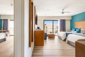 Habitación de hotel con dos camas, un escritorio, un televisor y un balcón con vistas.