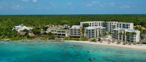 A resort with multiple buildings, a beach, and clear turquoise water.