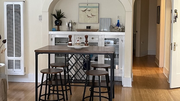 Una cucina con isola centrale, sgabelli da bar e lampadario a sospensione.